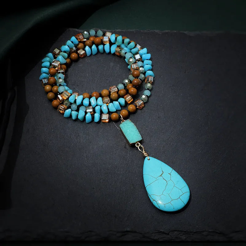 Turquoise blue large water drop pendant on a long mixed-material bead necklace.