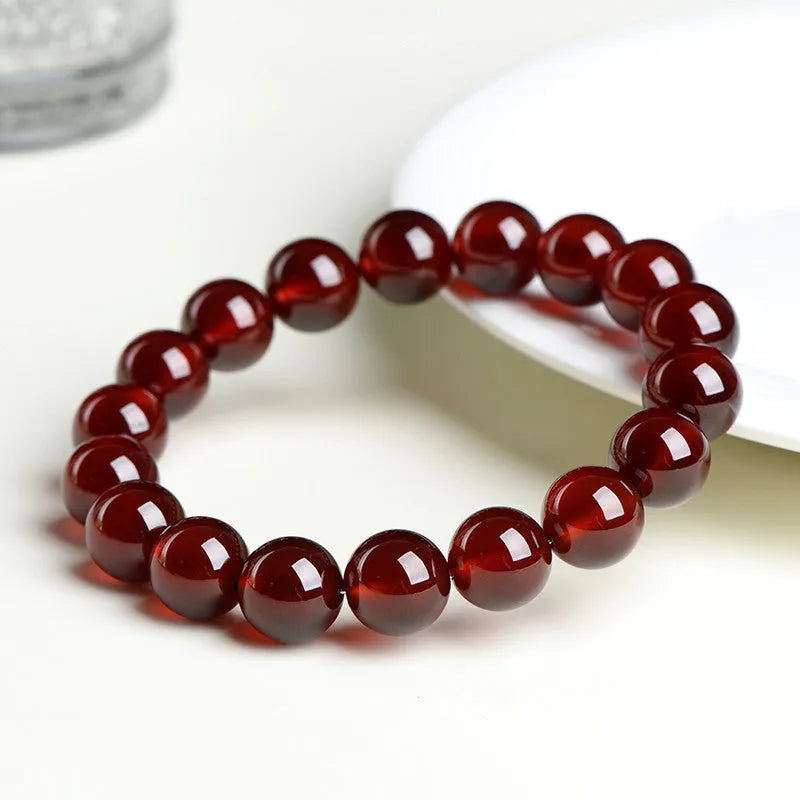 Natural orange red garnet crystal bracelet with Ruyi charms on a white background.