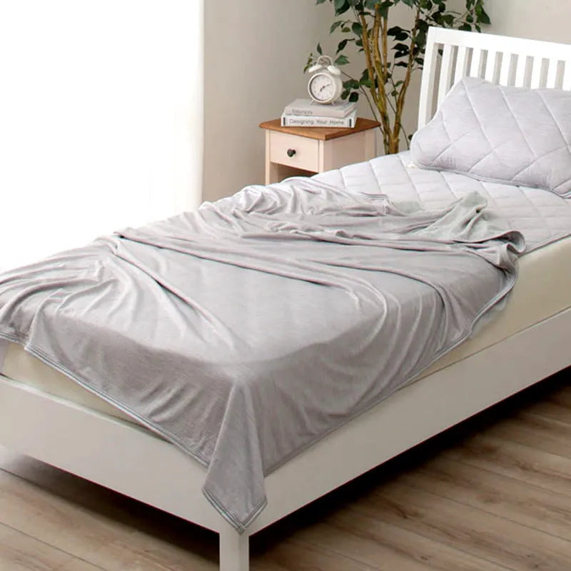 Blue and grey polyester cooling blanket with Japanese Q-Max fibres on a bed.
