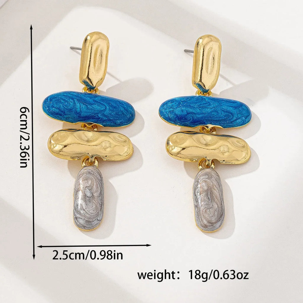 A pair of geometric-shaped stud earrings with a multicolour metallic finish on a plain background.