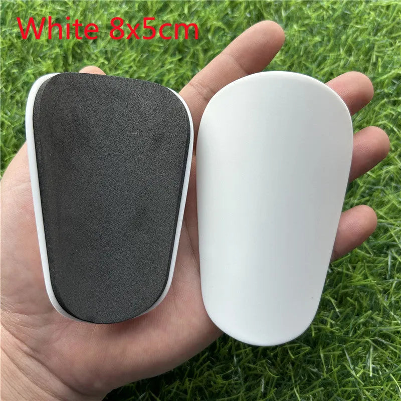 Extra small mini football shin guards measuring 8cm by 5cm in black and white plastic