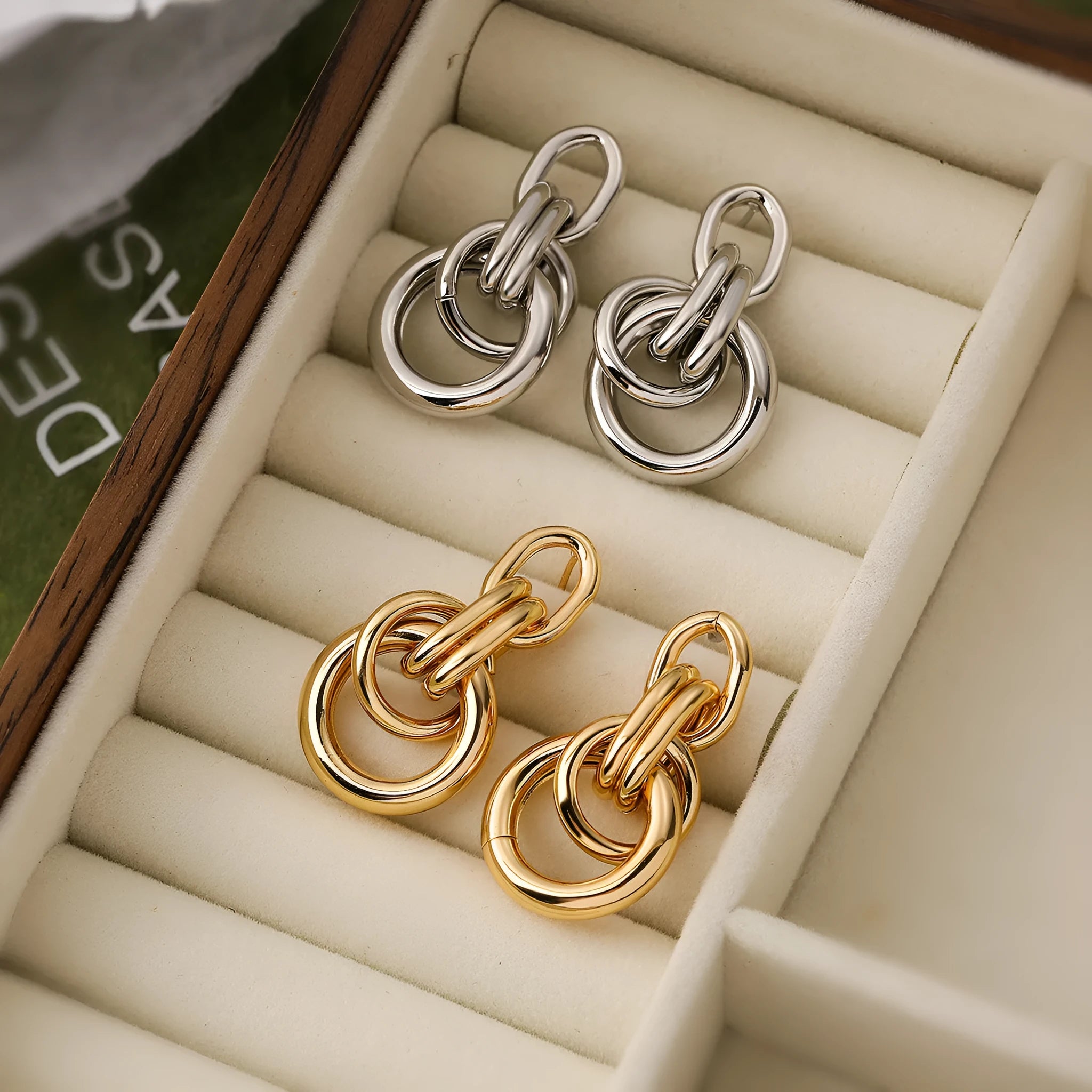 A pair of gold-coloured geometric earrings with an irregular shape on a white background.