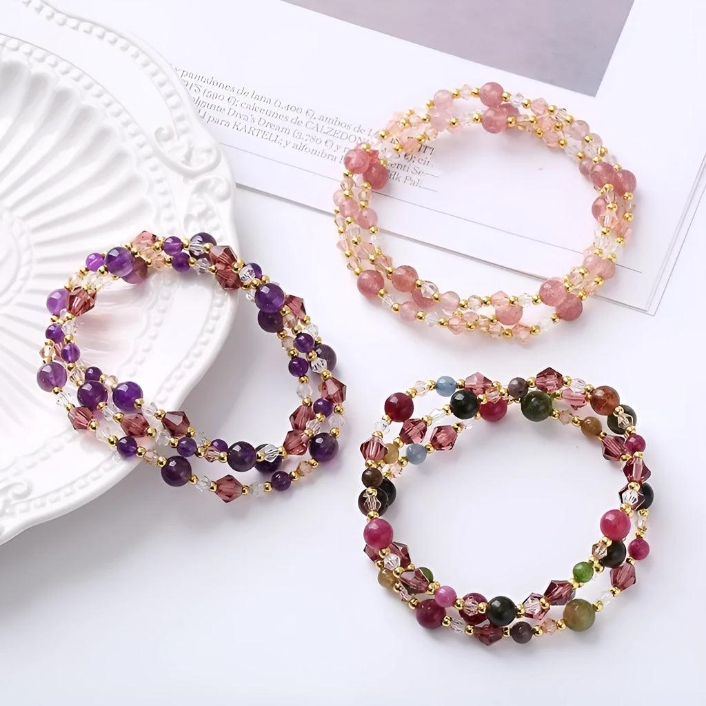 Close-up of a three-ring women's bracelet with tourmaline, strawberry quartz, and amethyst crystals on an adjustable rope.