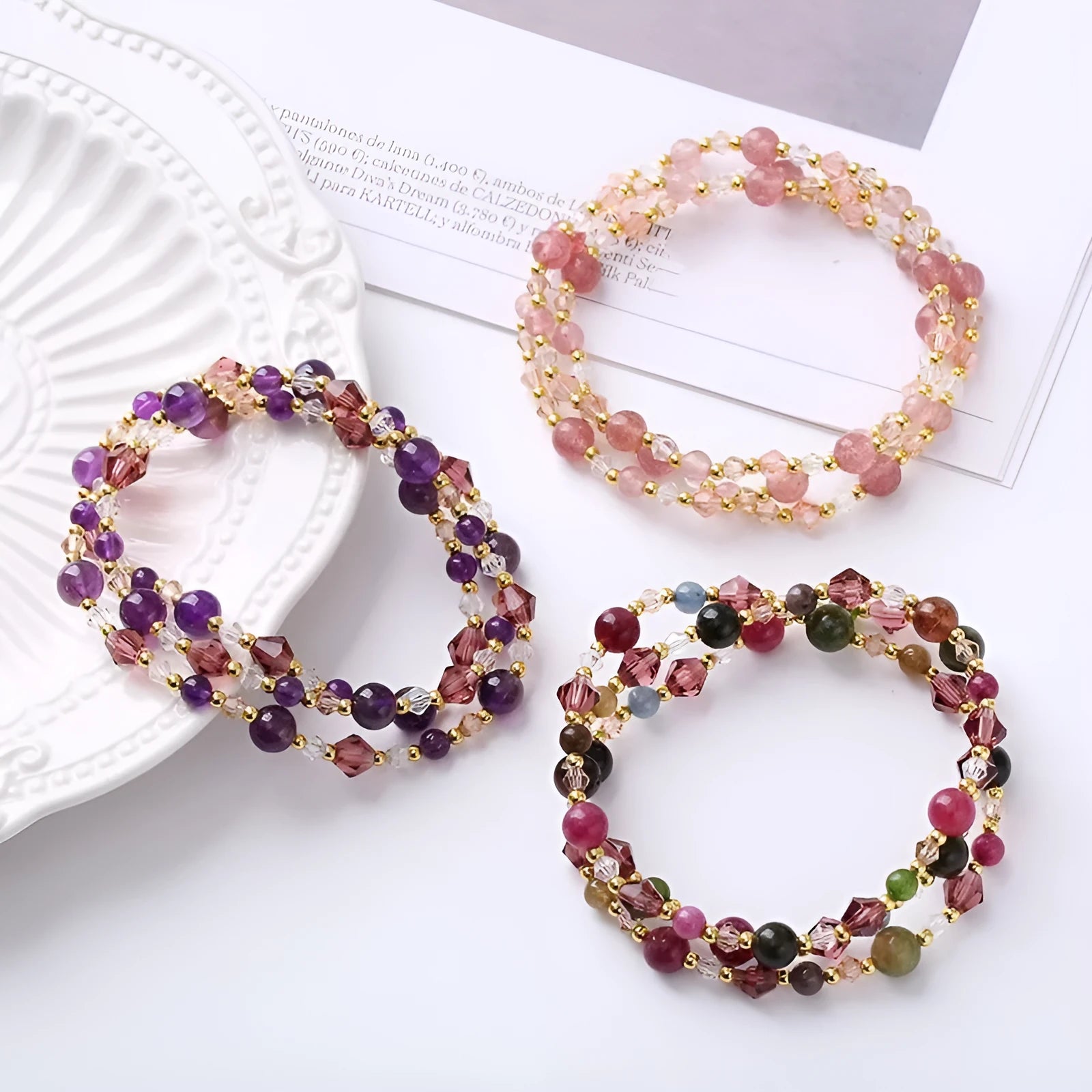 Close-up of a three-ring women's bracelet with tourmaline, strawberry quartz, and amethyst crystals on an adjustable rope.