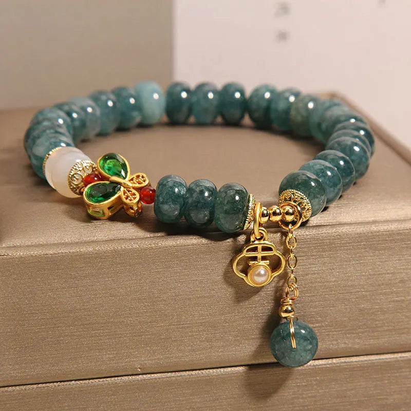 Blue water jade abacus beads bracelet with white agate, butterfly motifs and rhinestone accents on alloy band