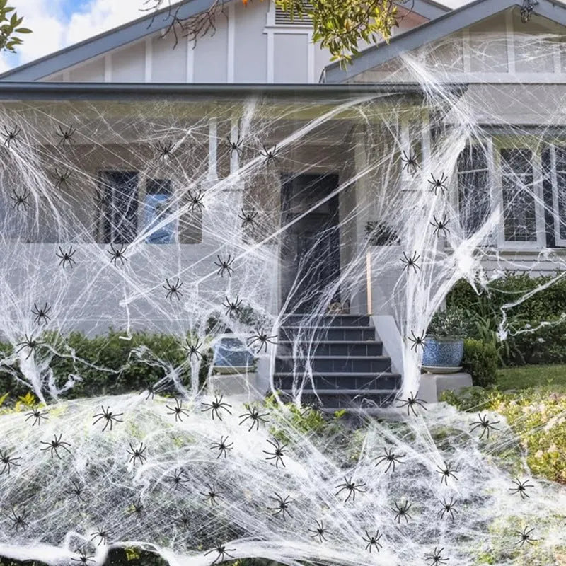 White cotton spider web Halloween decoration with plastic spiders draped over a surface.