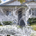 White cotton spider web Halloween decoration with plastic spiders draped over a surface.