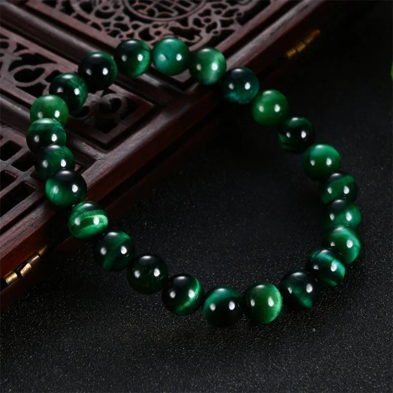 A natural green tiger eye stone bracelet with polished geometric beads on a wrist.