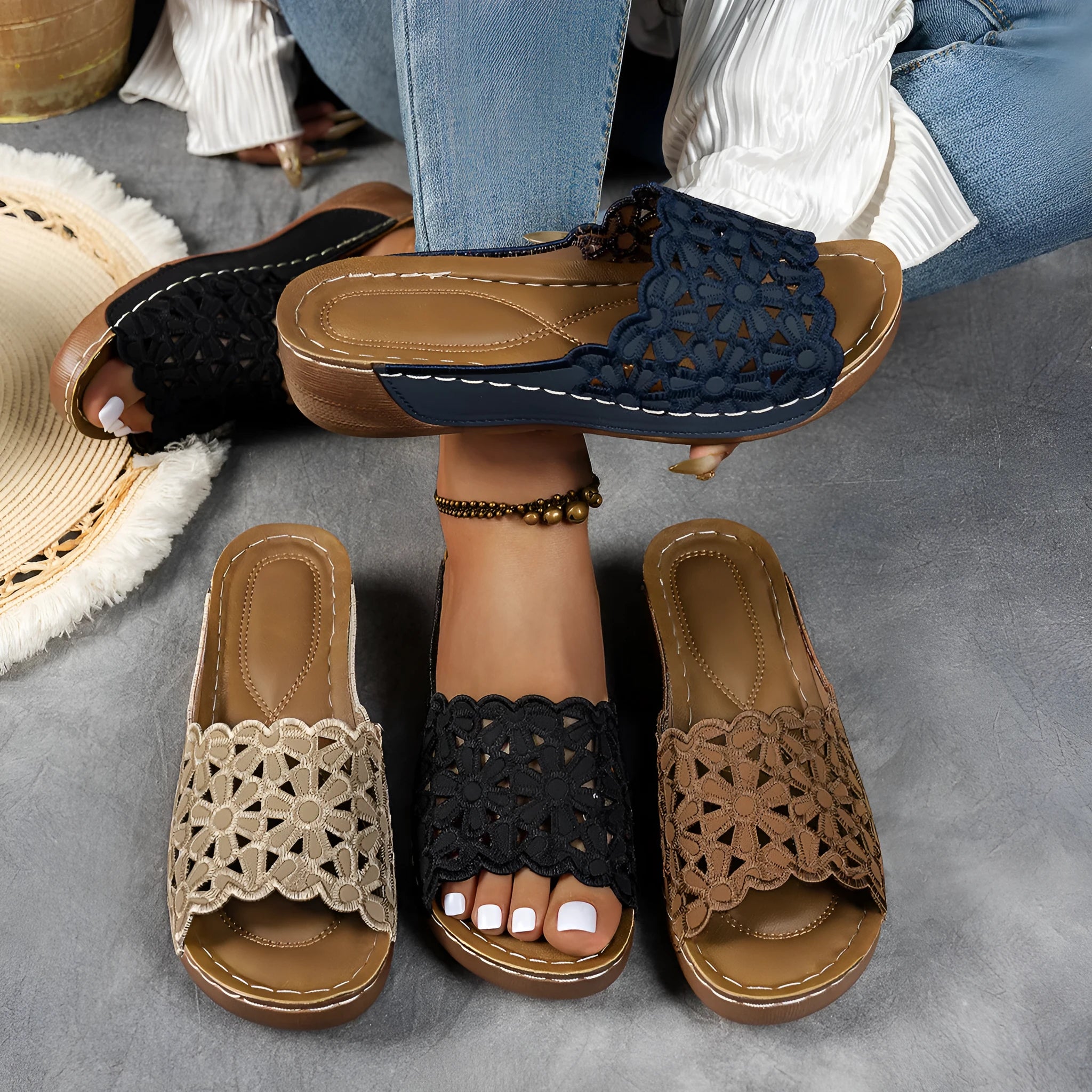 Women's black wedge beach slippers with floral cutouts on the PVC upper and a rubber sole.