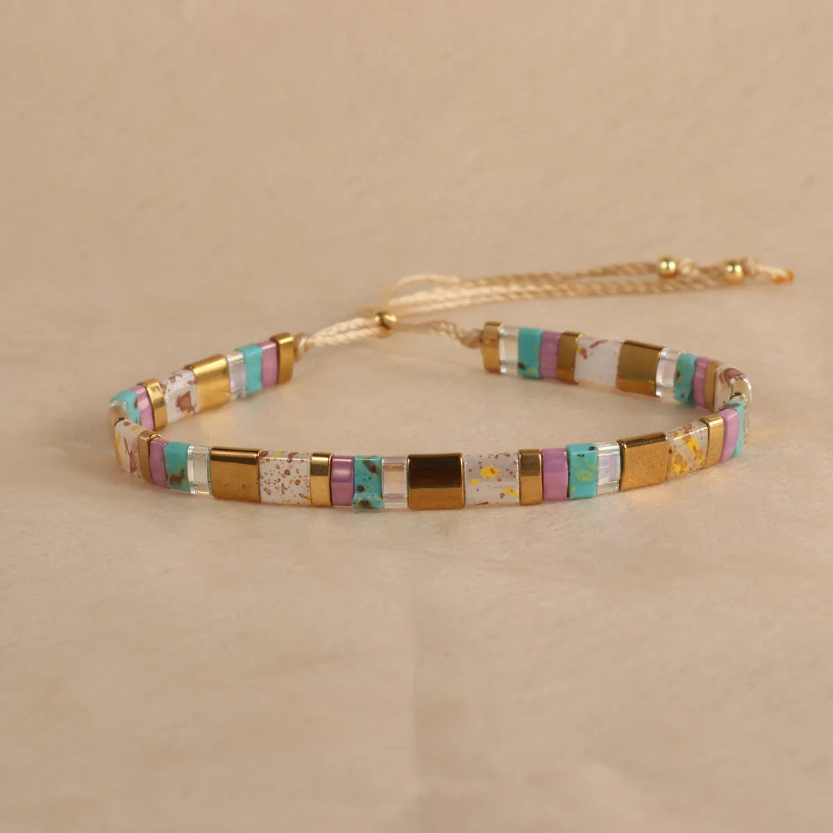 Adjustable geometric beaded bracelet with pull beads in milky white, black, green, blue or red.