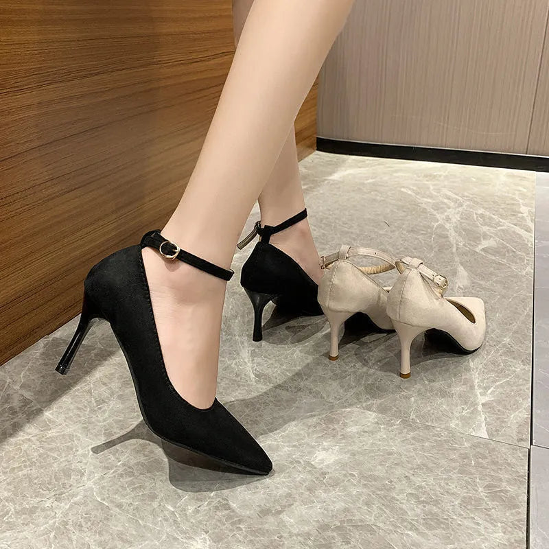 Women's black stiletto pump with skull pattern and buckle decoration on a white background.