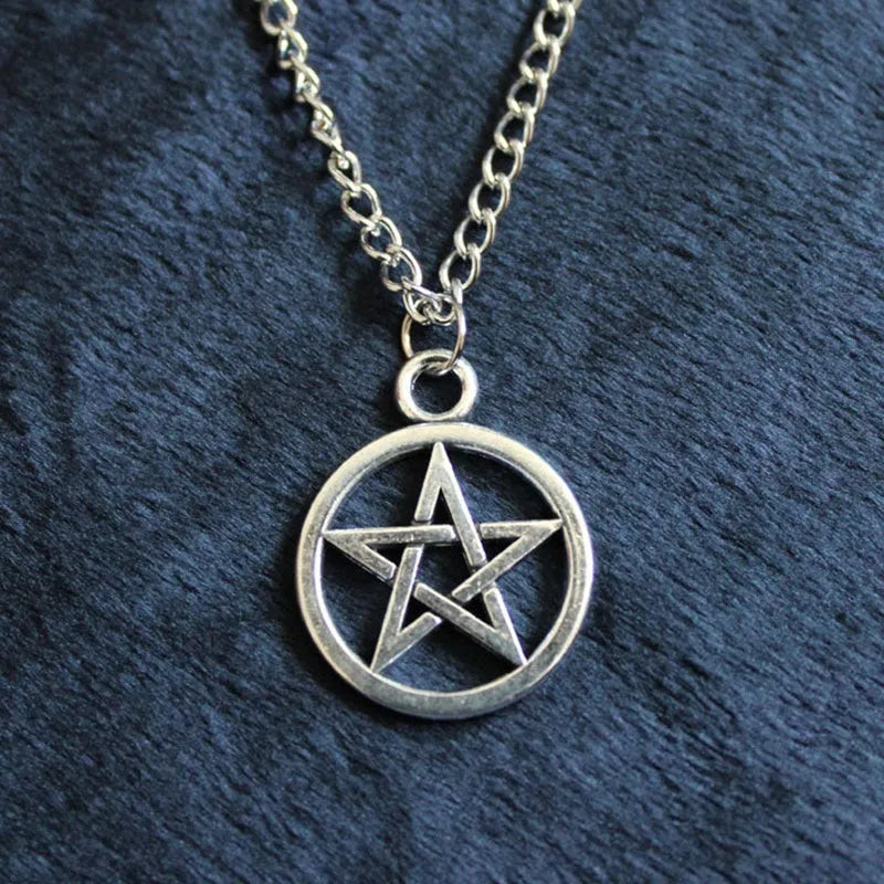 Vintage pentagram necklace on alloy adjustable chain, bronze finish, lying flat on grey surface