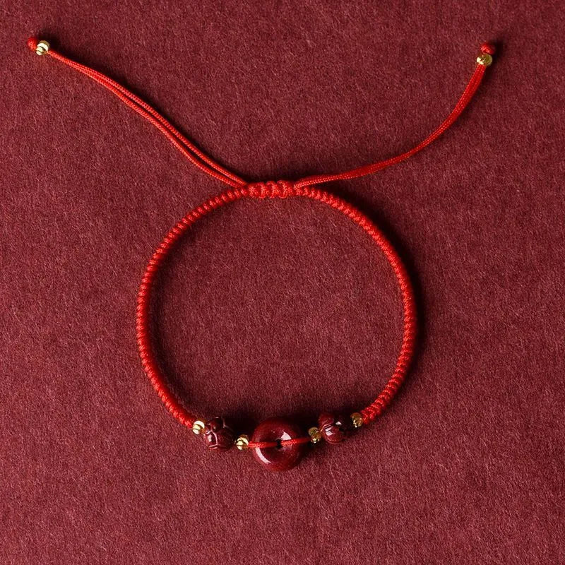 Traditional Chinese cinnabar bracelet with heart-shaped centrepiece and peace buckle clasp on coloured rope cord