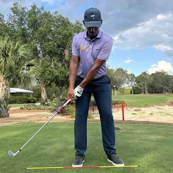 Plastic golf swing plane trainer simulator on a plain background.