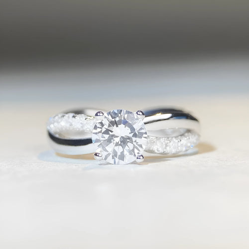 Geometric twisted silver band ring with a 1 karat moissanite stone in a four-claw setting.