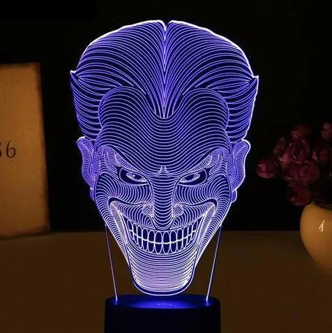 A 3D LED table lamp showing multiple colour lights, sitting on a square base with a USB cable and remote control.