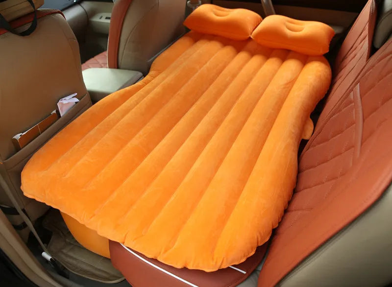 Black inflatable car bed with flocked surface and pillows set up in a car's back seats