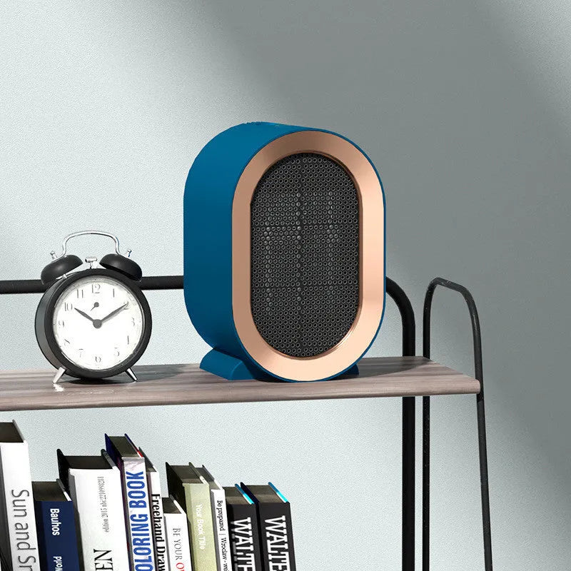 Compact black desktop ceramic fan heater with mechanical control dials, placed on a wooden desk.