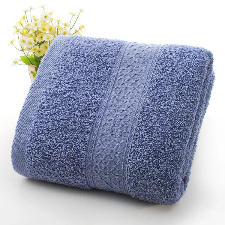 A pile of thickened cotton bath towels in various colours including apple green, dark blue, and light pink.