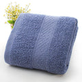 A pile of thickened cotton bath towels in various colours including apple green, dark blue, and light pink.