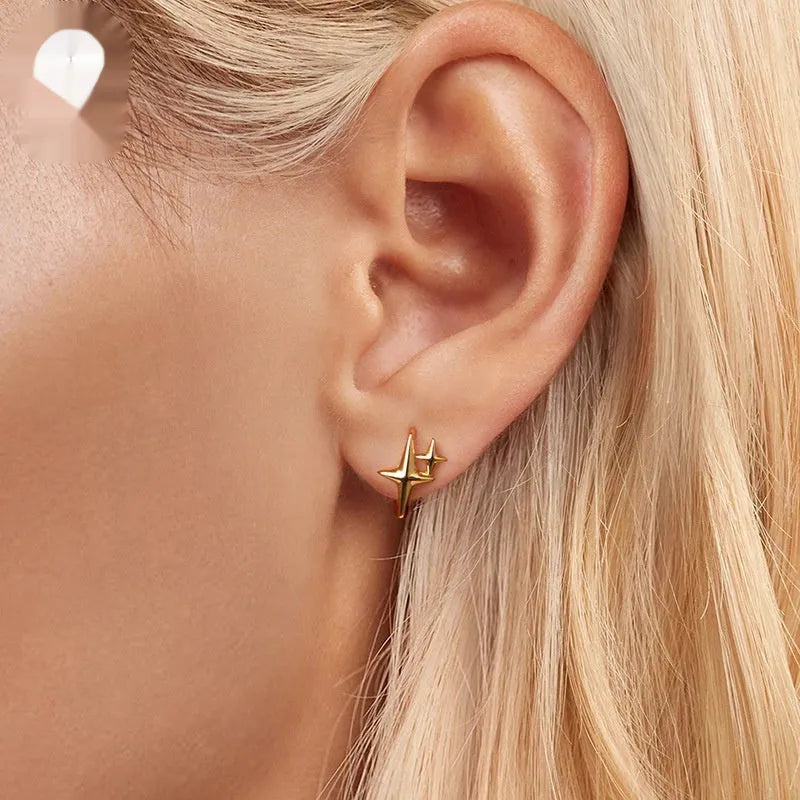 Minimalist star-shaped silver ear clips with an oxidised finish and XINGX design detail.