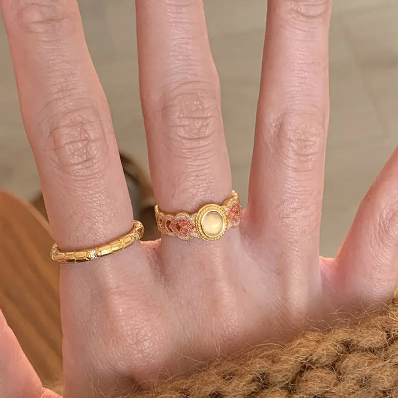 A pink crystal enamel ring with a geometric gold-plated copper band and an open mouth adjustable design.