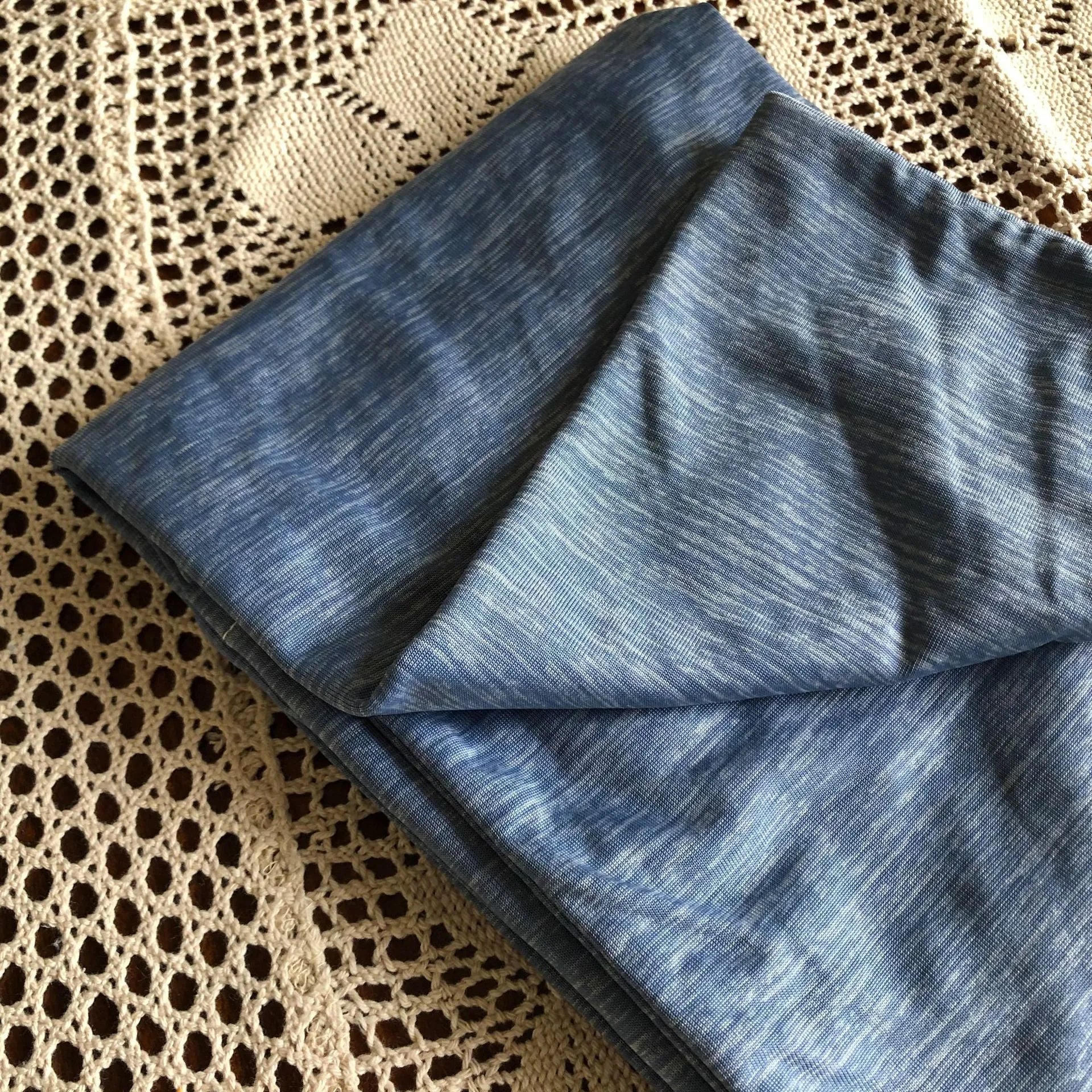 Blue and grey polyester cooling blanket with Japanese Q-Max fibres on a bed.