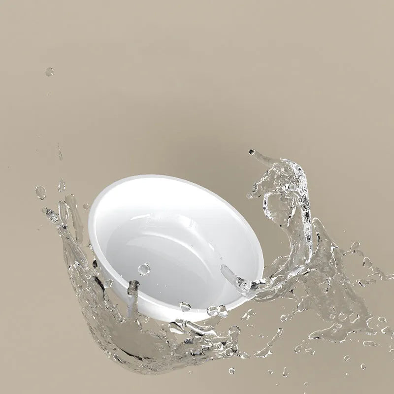Green tilted stainless steel cat bowl on a white surface.