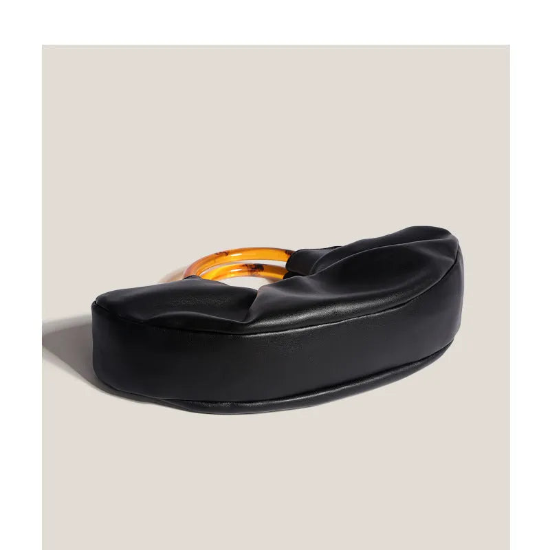 Niche horn bag in black or white PU leather with acrylic ring handle and fold detail for daily matching.