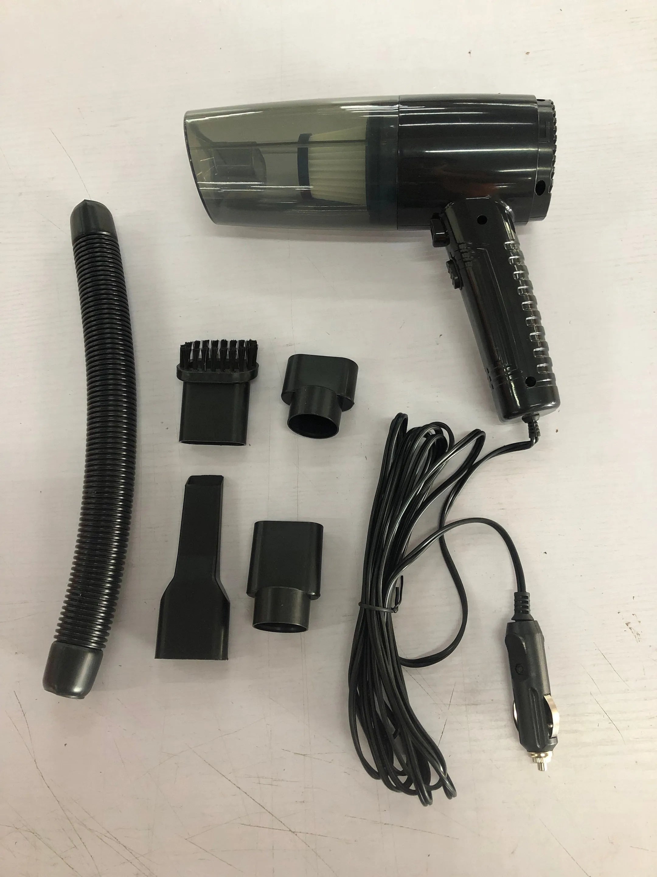 Black and white 12V car vacuum cleaner with long cord and set of five suction attachments.