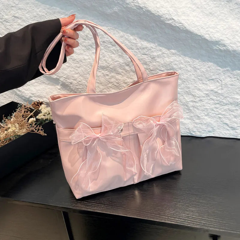 Black college-style tote bag with large capacity, a bow detail, and two shoulder straps.