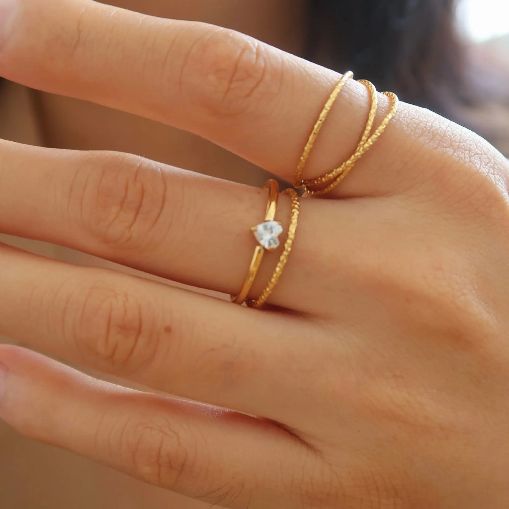 Golden love heart and oval stainless steel ring for women on a white background.