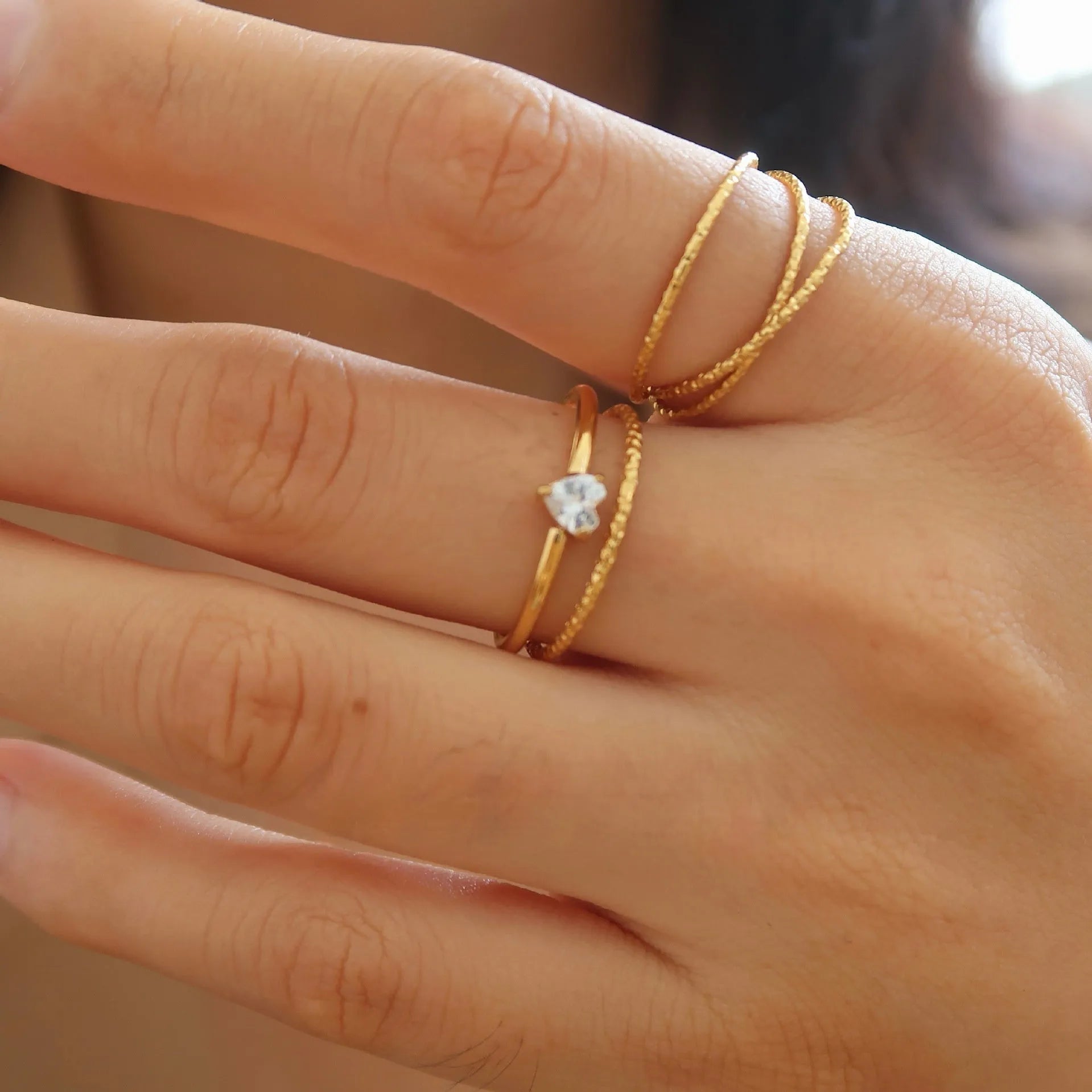 Golden love heart and oval stainless steel ring for women on a white background.