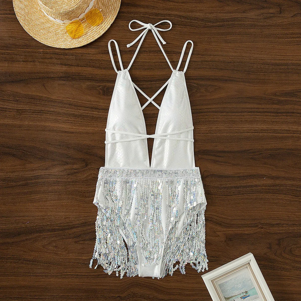 White one-piece swimsuit with a deep V-neckline and a tassel detail.