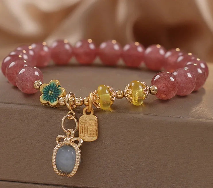 Red bracelet with strawberry quartz beads, alloy metal spacers, and rhinestone decorative details.