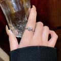 Adjustable copper open ring with electroplated gold or silver finish and geometric bow design, front view