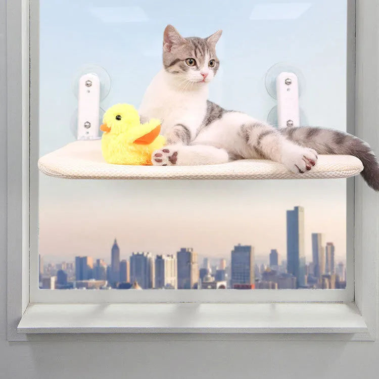 Stainless steel foldable cat window hammock with suction cups and a grey plush cushion attached to a glass pane.