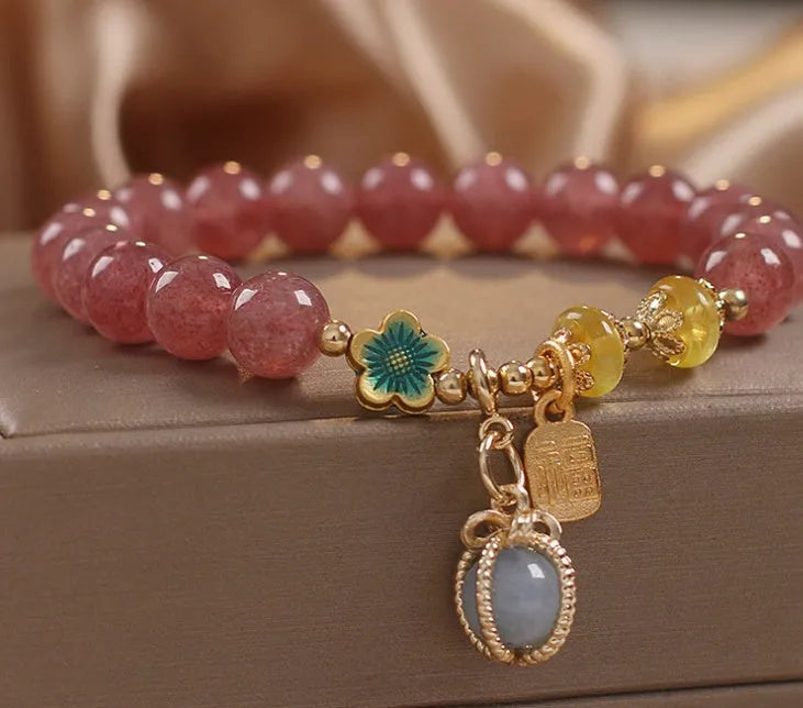Red bracelet with strawberry quartz beads, alloy metal spacers, and rhinestone decorative details.