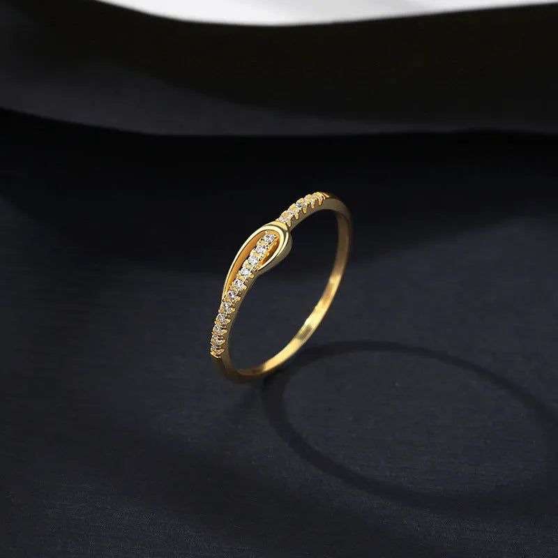 S925 silver bow ring with single row of diamond stones on a plain background
