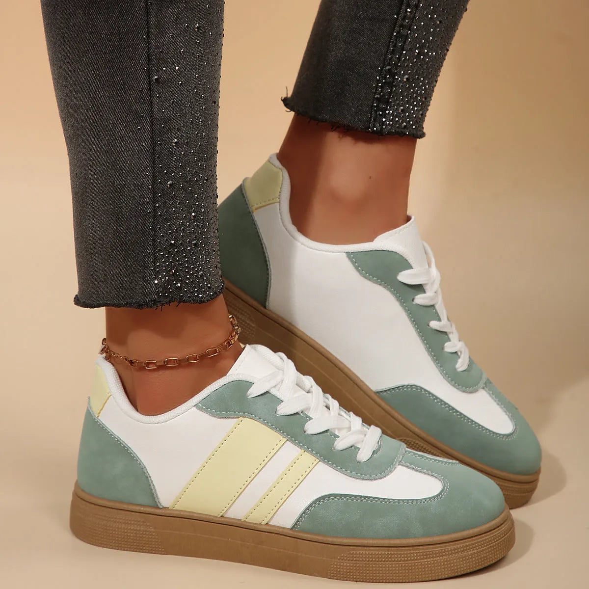 Green women's retro low-top trainers with cross-strap detail and round toe on a white background.