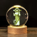 White crystal decorative ball with cross scenes on a wooden warm light base.