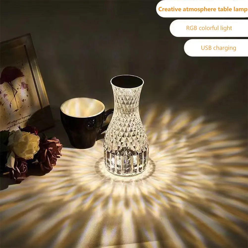 Transparent vase-shaped crystal LED table lamp on a table, showing soft coloured light.