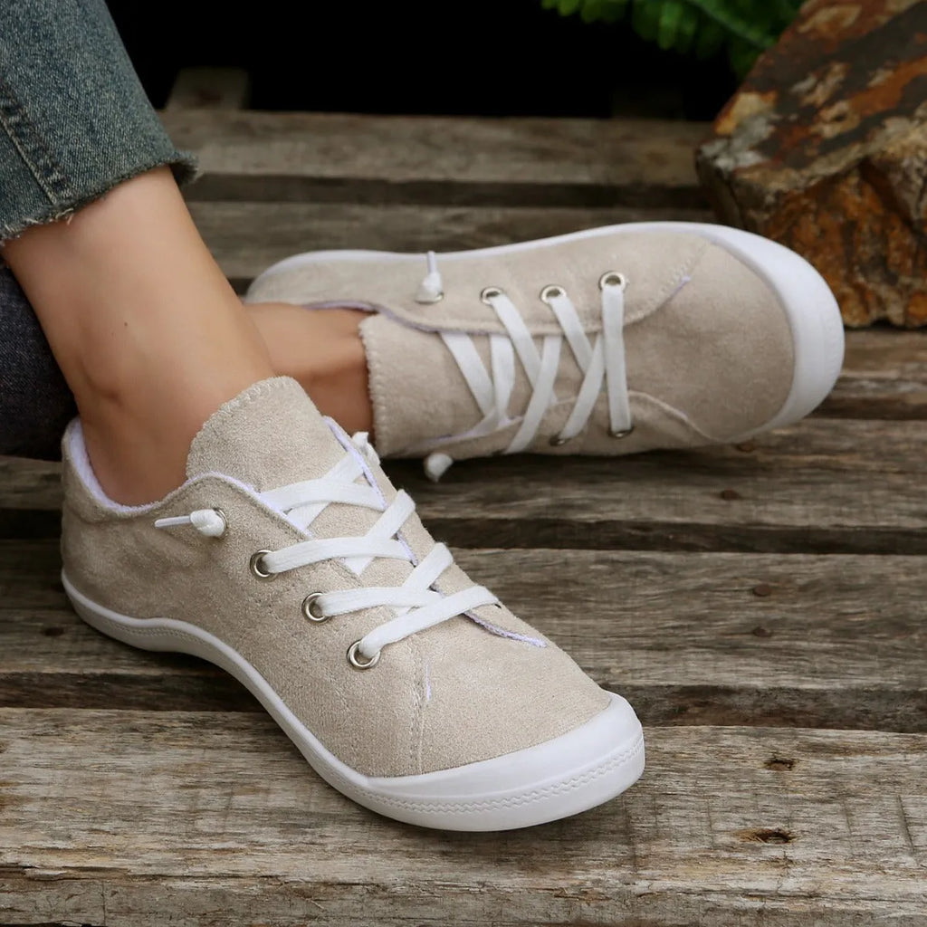 Women's creamy white low-top fabric casual sneakers with a rubber sole on a neutral background.