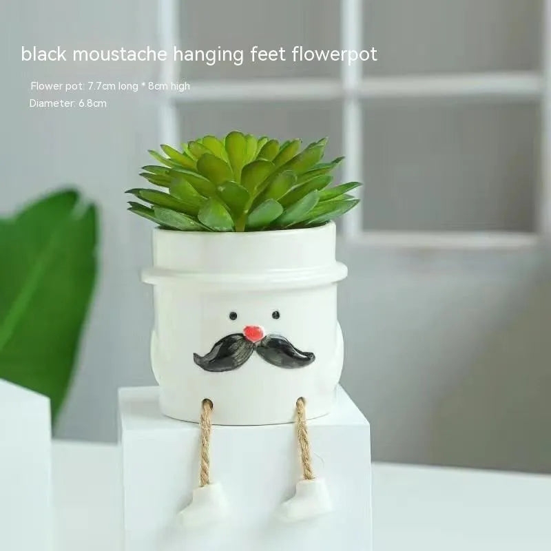 Ceramic hanging foot flowerpot in a cartoon style, shown on a desktop with a small succulent plant.