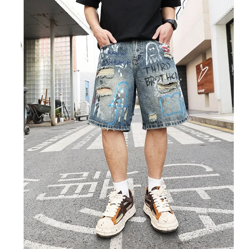 Blue denim shorts for men with rips and a graffiti pattern, featuring a zipper fly.