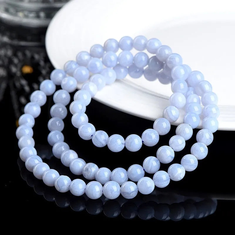 Close-up of a blue agate bracelet with scattered beads and striped spheres on a wrist.