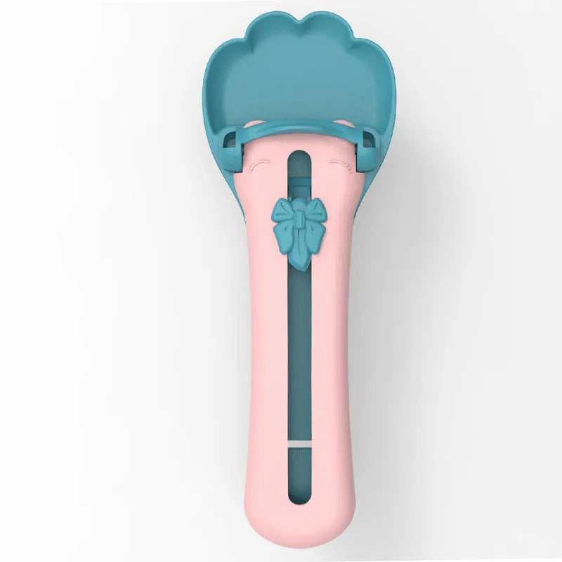 Green and pink pet food squeezer spoon for dispensing treats and liquid food to cats and dogs.