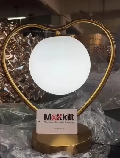 Clear acrylic heart-shaped LED lamp with remote control on a wooden table.