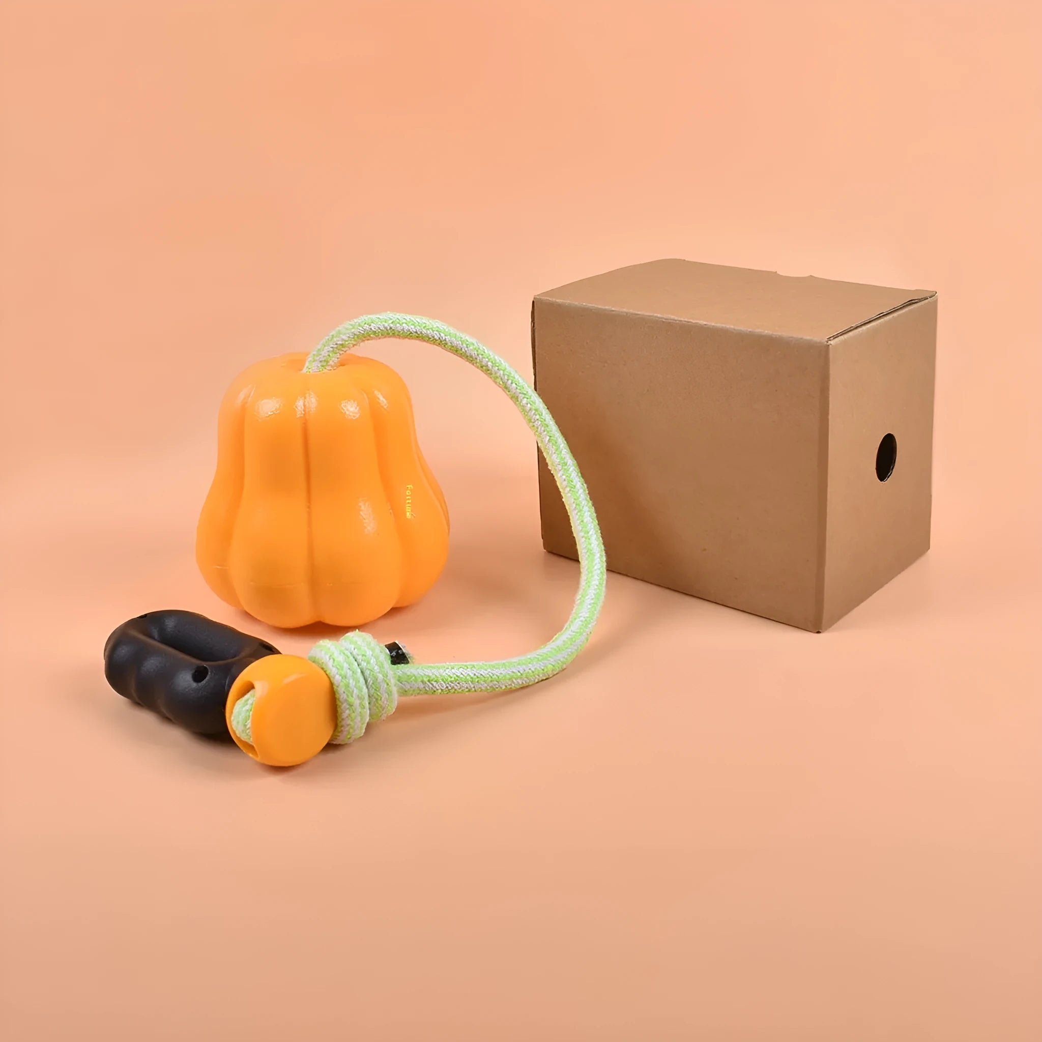 Orange plastic molar-shaped dog chew toy with a blue rope attached, on a green background.