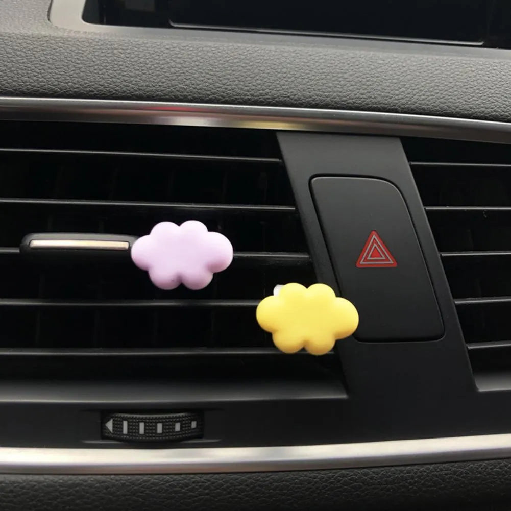 Small colourful resin car fragrance clip shown in multiple colours on a car air vent.